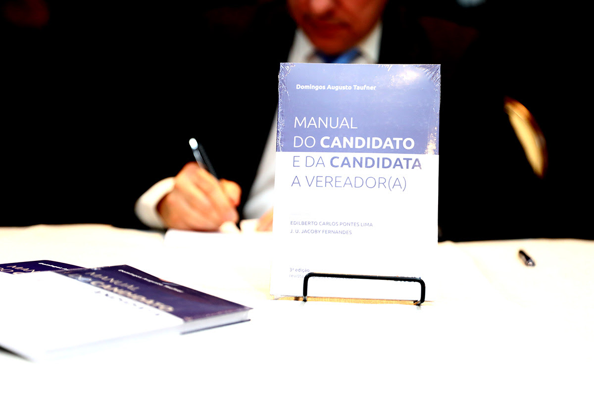 Autor Domingos Taufner autografa o livro "Manual do candidato e candidata a vereador(a)", de sua autoria.